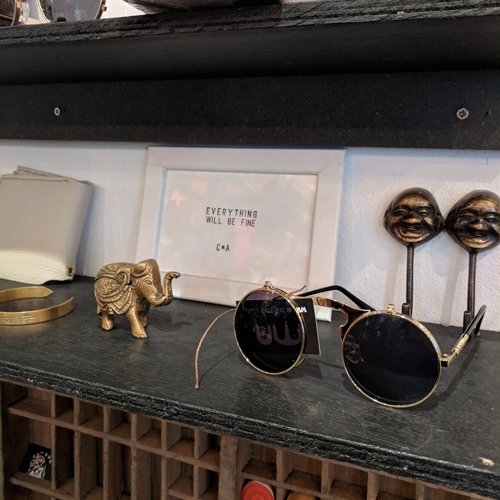 Vintage sunglasses on a shelf with golden elephant and art print