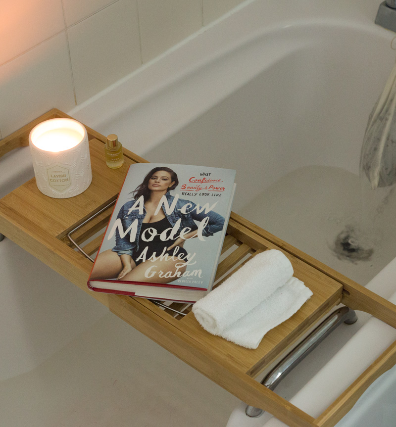 Ashley Graham book on a bath shelf next to a candle
